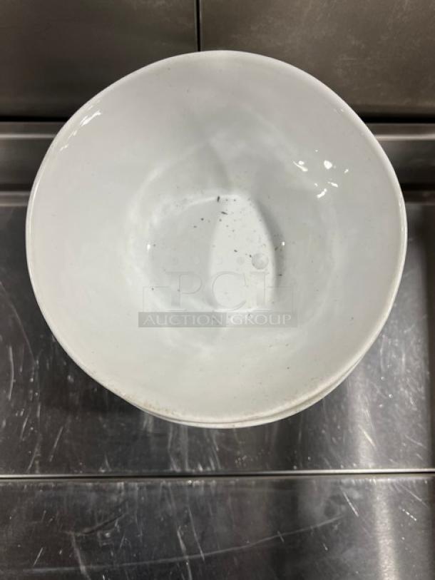 Crate&Barrel white round bowl, commercial grade. Slightly worn with visible specks. Ideal for various dining settings.