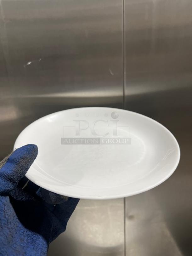 Fortessa commercial white round plate in pristine condition, held in a gloved hand.