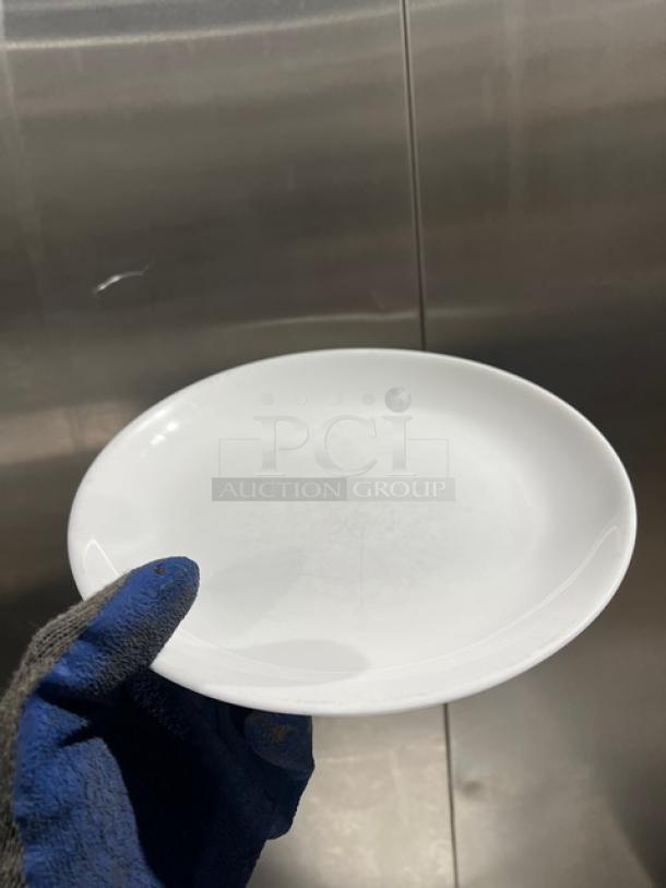 Fortessa commercial white round plate, slightly used, held by gloved hand.