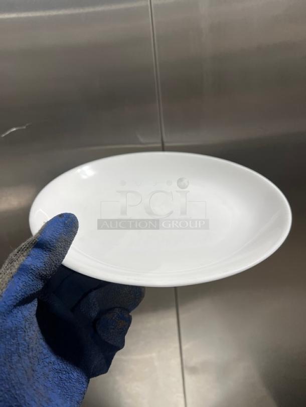 Fortessa Commercial white round plate, pristine condition, smooth finish, shown by a gloved hand.