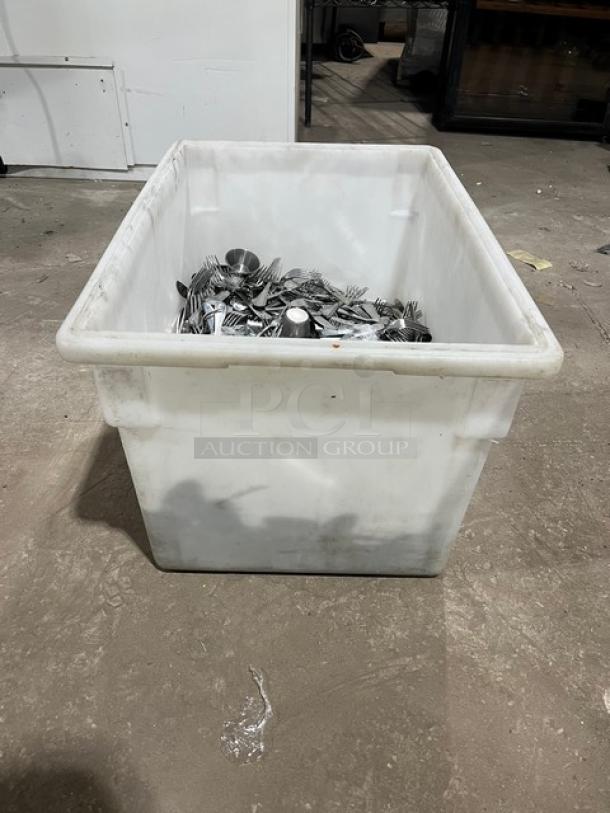Stainless steel dining utensils in a white bin, includes forks, knives, spoons. Used condition, ideal for commercial use.