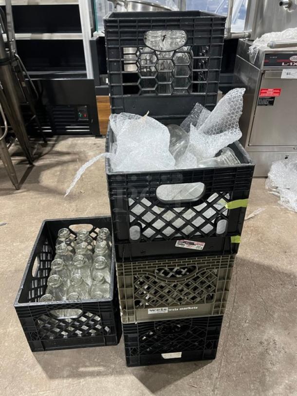 Auction item: Commercial water/juice serving bottles in 8 crates. Bottles are transparent glass, wrapped in bubble wrap, in good condition.