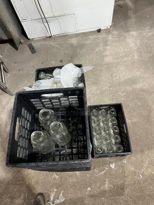 Eight crates of commercial water/juice serving bottles, clear glass, varied sizes, wrapped for protection, excellent condition.