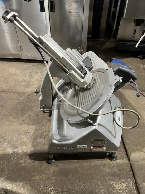 Hobart commercial electric deli meat slicer, heavy-duty countertop model, features visible. Good condition with labels.