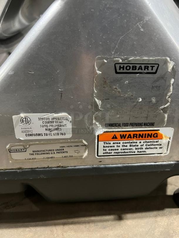 Hobart commercial electric deli meat slicer with visible warning and compliance labels. Used, heavy-duty model.