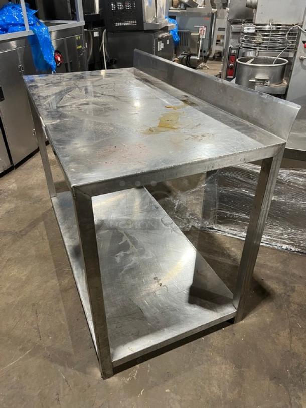 Commercial stainless steel food prep work table with undershelf, scratched top, rear backsplash, sturdy frame, fair condition.