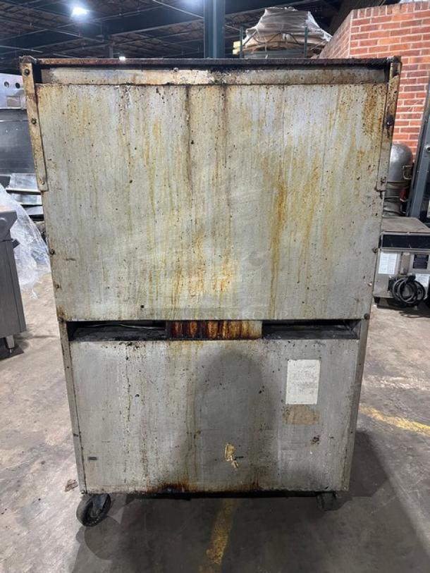 Southbend commercial stainless steel 6-burner range/oven with backsplash, overhead salamander shelf, and casters. Visible wear and rust on surface.