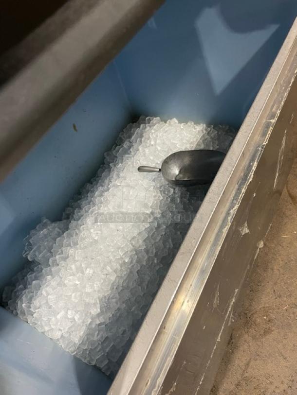 Hoshizaki IM-500SAA ice machine bin filled with cubed ice, includes ice scoop. Commercial grade, stainless steel, on legs.