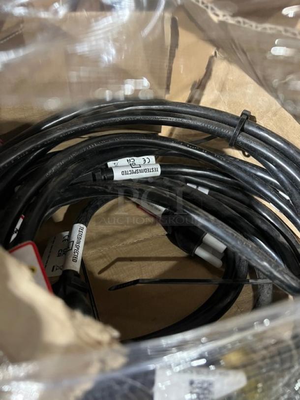 Coiled black cables with labels inside a cardboard box, new condition.