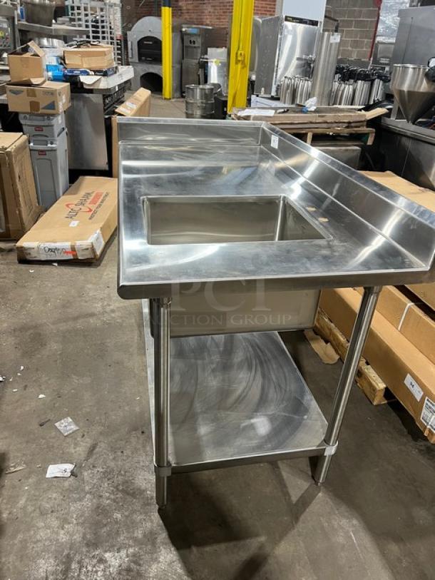 Brand new Advance Tabco stainless steel worktop table with right-side sink, undershelf, and splash guards, on legs.