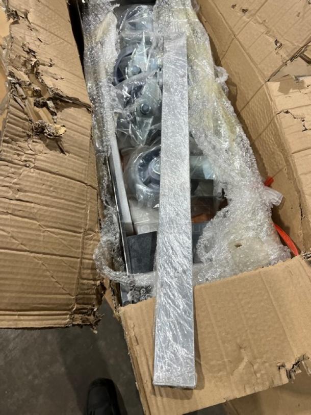 Brand new commercial double convection oven stacking kit with casters, partially unpacked in cardboard box.