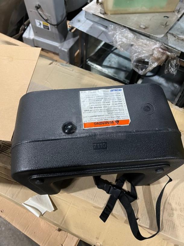 Brand new Carlisle 7114 black polypropylene dual-sided booster seat with safety strap, warning label, and model marking.