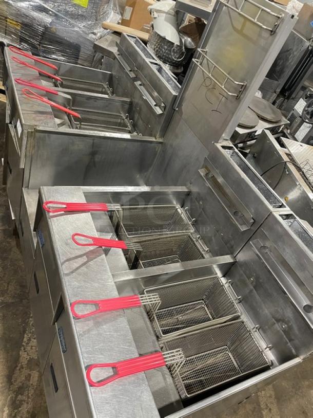 Pitco FGSGH50 stainless steel 4-bay deep fryer system, natural gas, with center basket hanger, splash back, and casters.