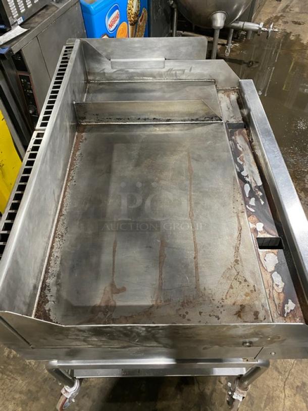 WoodStone stainless steel natural gas countertop plancha griddle. Features back & side splash, single undershelf cart, casters. SN: GP1B16MAY1704992. Used condition.