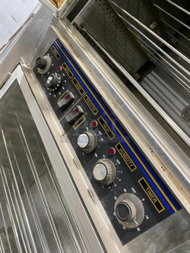 Nu-Vu SUB123 stainless steel convection oven/proofer combo on casters, with wired racks, visible control panel dials, 208V 3-phase.