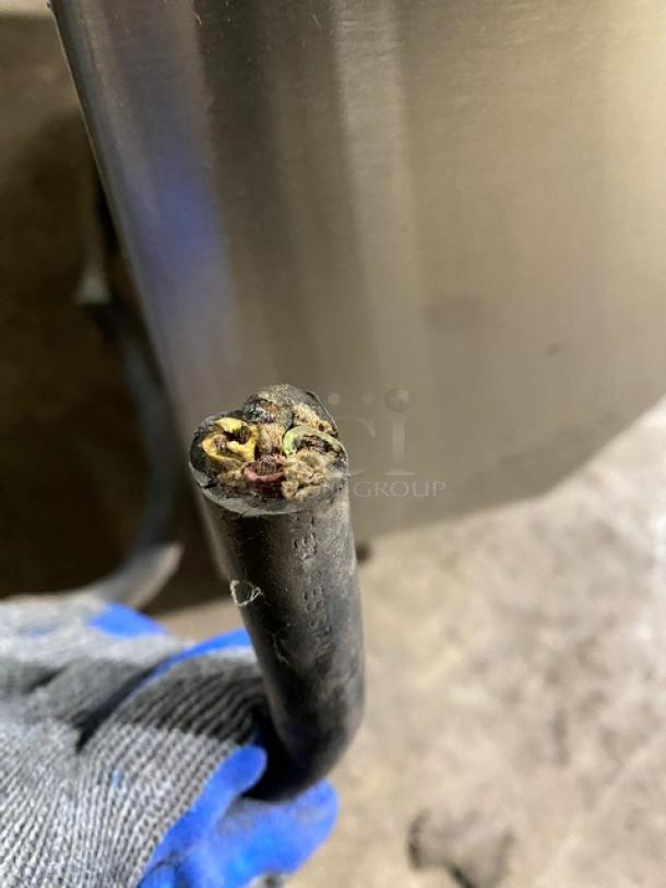 Close-up of the power cable for a Fetco CBS2052 coffee machine. Visible wires suggest potential repair needed.