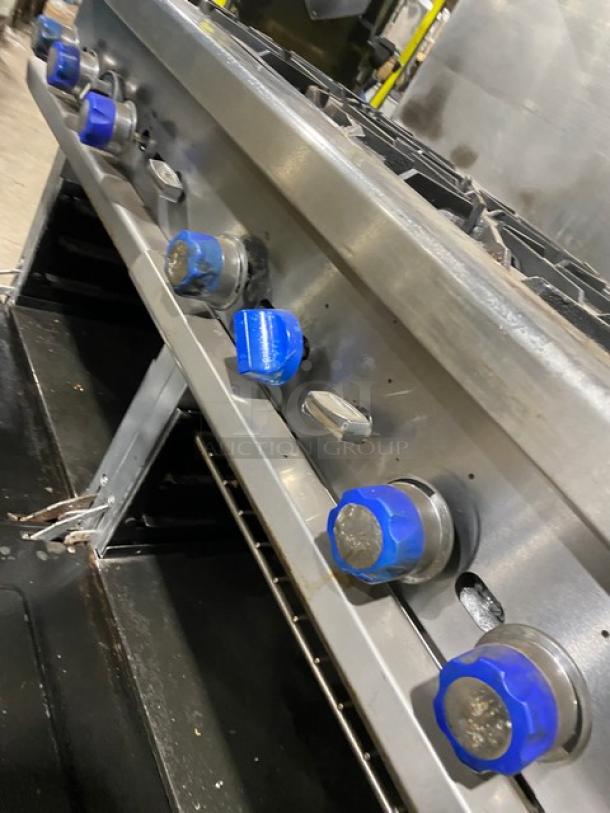 American Range stainless steel 8-burner range with blue knobs, double oven, backsplash, overhead salamander shelf, on casters.