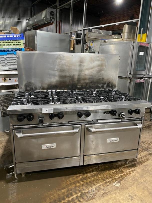 Garland commercial stainless steel gas 10-burner range with double oven, backsplash, and wired rack, on sturdy legs.
