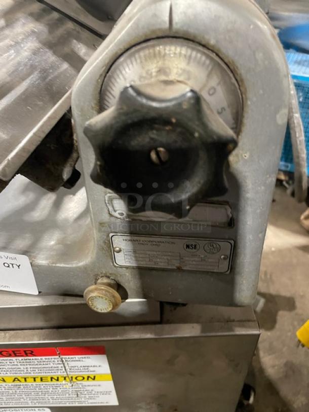 Hobart 1612E commercial electric deli meat slicer, with adjustment dial and NSF certification plate visible.