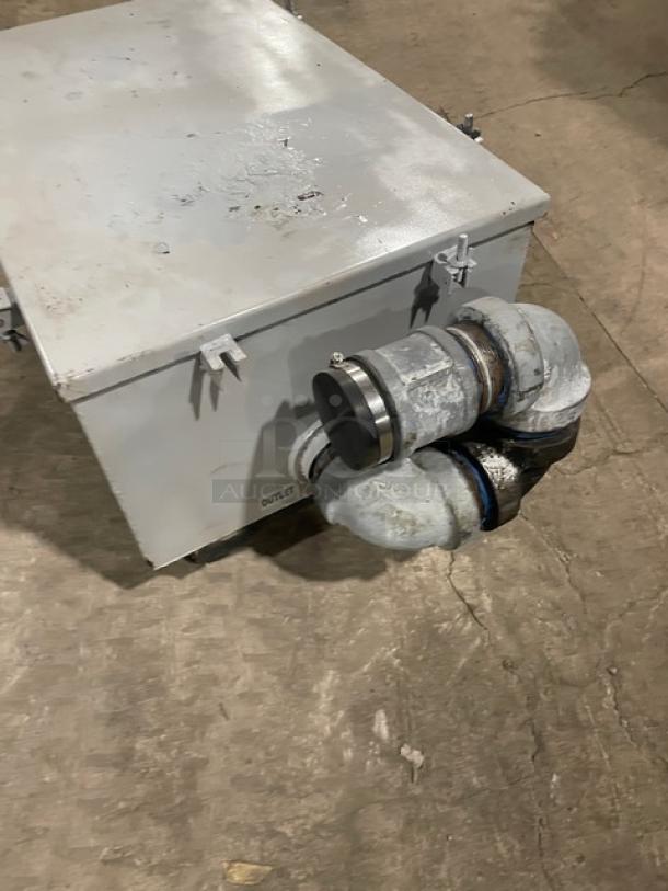 Commercial heavy-duty grease trap/interceptor, metal construction, dual pipe connections, signs of wear, labeled "OUTLET."