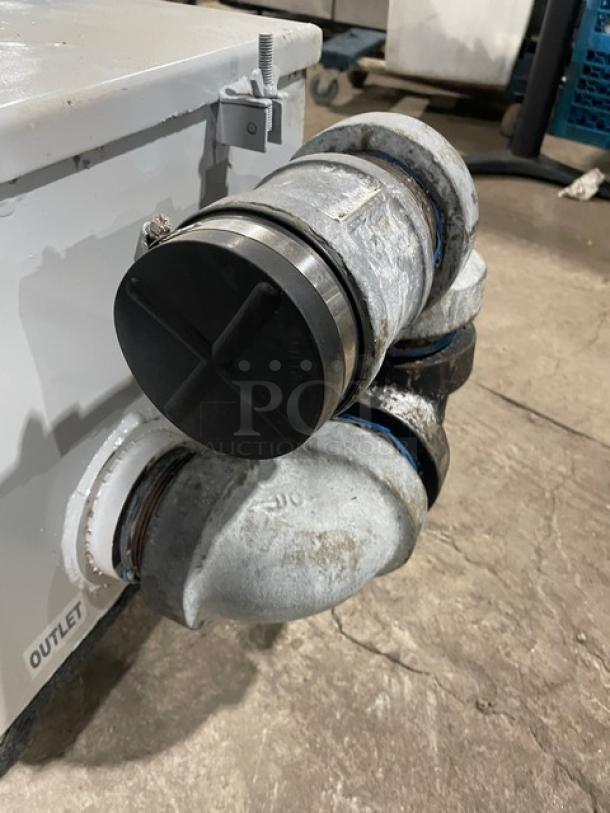 Commercial heavy-duty grease trap/interceptor with durable piping, outlet label, and signs of use. Designed for efficient grease management.