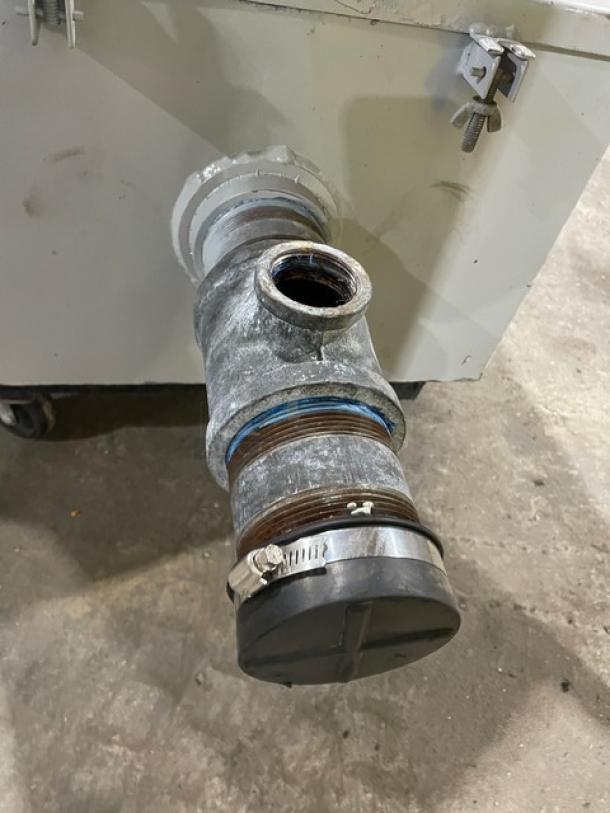 Commercial heavy-duty grease trap/interceptor with visible pipe connections, showing signs of use. Sturdy metal construction.