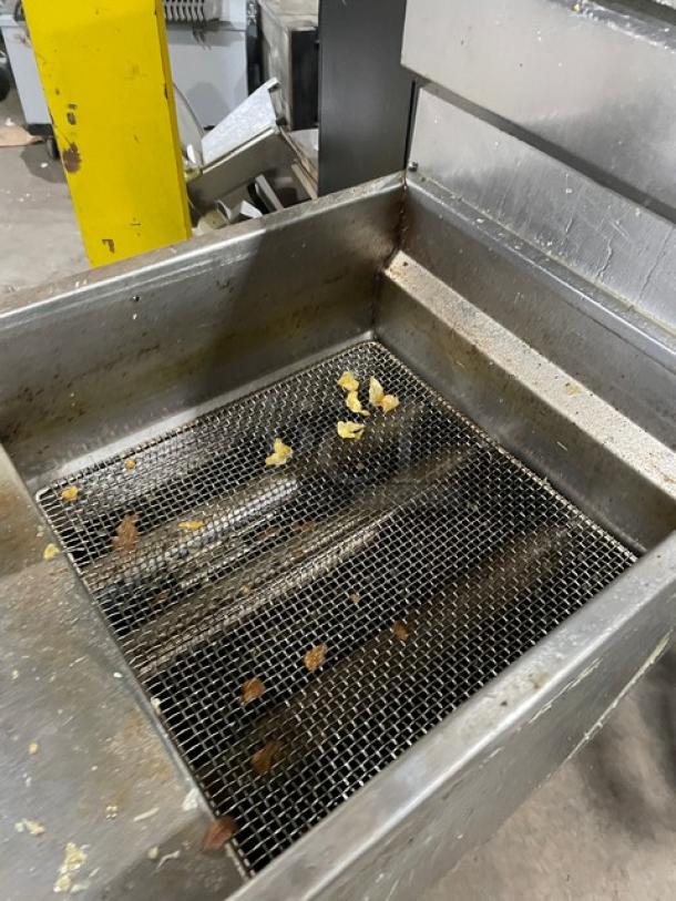 DCS stainless steel gas fryer with backsplash and basket hanger, on legs. Used condition with visible food remnants.