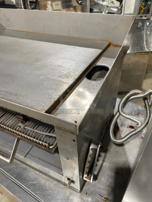 Commercial stainless steel gas countertop flat-griddle with back and side splash, built-in broiler/cheese melter, used condition.
