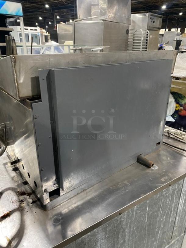 Commercial stainless steel gas-powered countertop flat-griddle with back and side splash. Features built-in broiler/cheese melter.