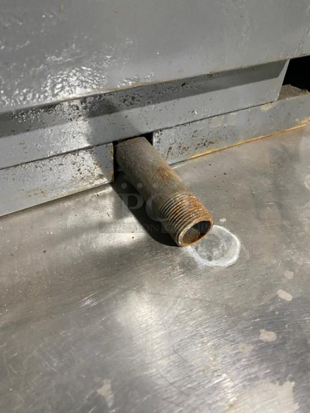 Commercial stainless steel gas-powered countertop griddle with broiler. Features back and side splash. Shows wear.