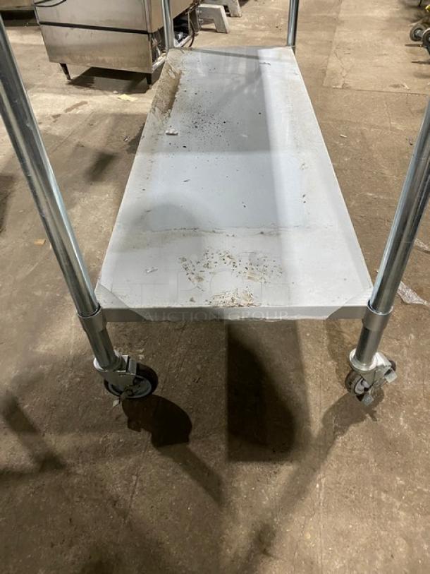 Commercial stainless steel worktop table with single undershelf, featuring casters for mobility. Good condition, some surface wear.
