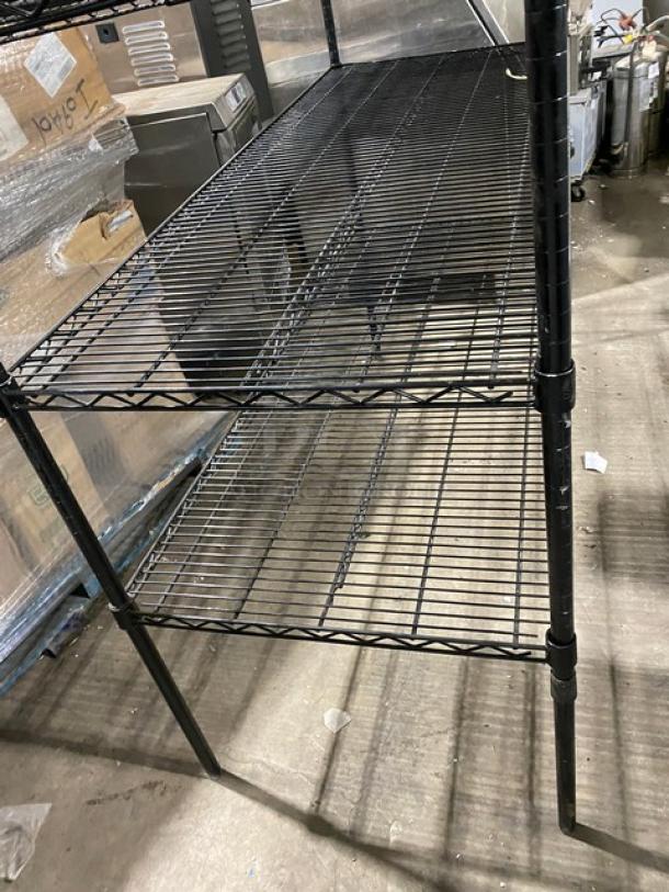 Commercial black multi-tier wired storage rack, utility shelving on legs. Durable steel construction, three tiers, excellent condition.