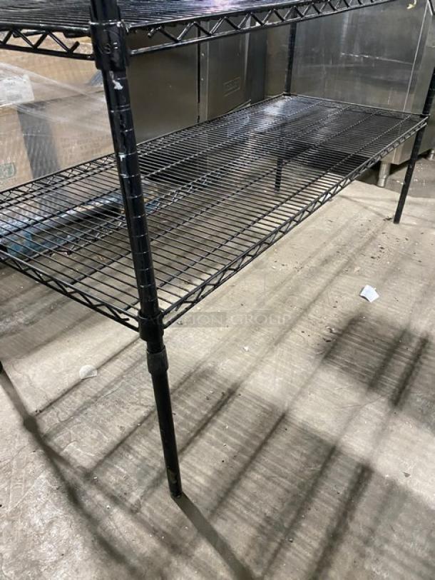 Commercial black multi-tier wired storage rack with legs, in good condition. Ideal for utility shelving.