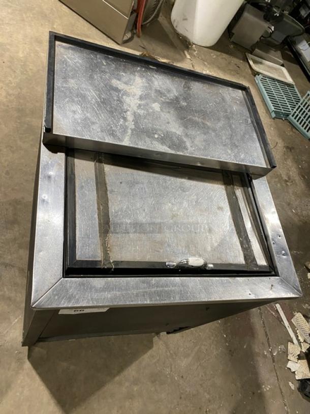 True Model TD2407 black bottle cooler with stainless steel sliding top lid. 24.5", 115V, 1 Phase. Visible wear on lid.