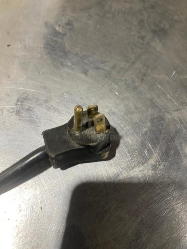 A close-up of a power plug for a Beverage-Air UCR27A commercial refrigerator. Plug appears used.