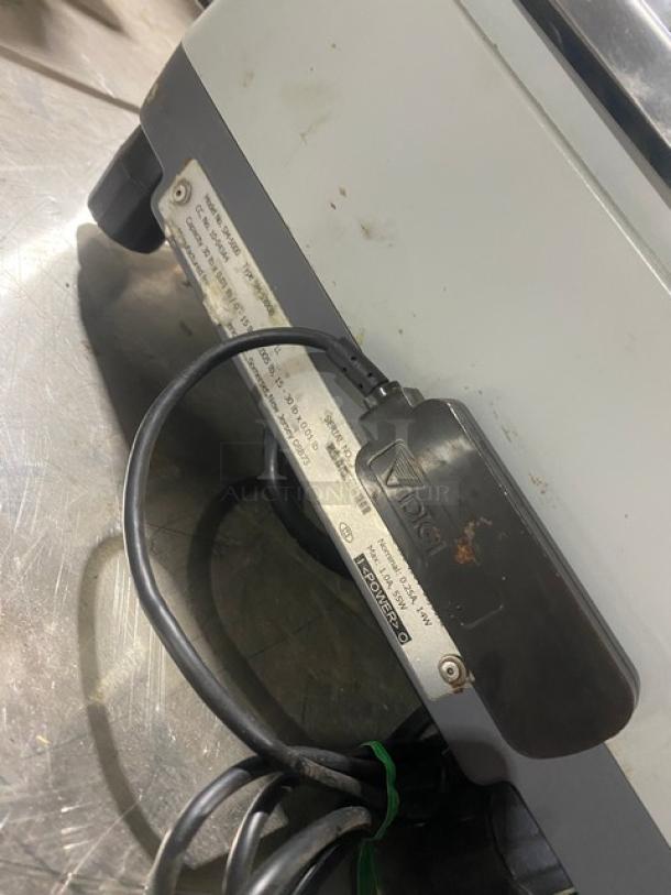 Digi SM5000 stainless steel electric retail scale on legs, with visible power cord and label indicating model and voltage.