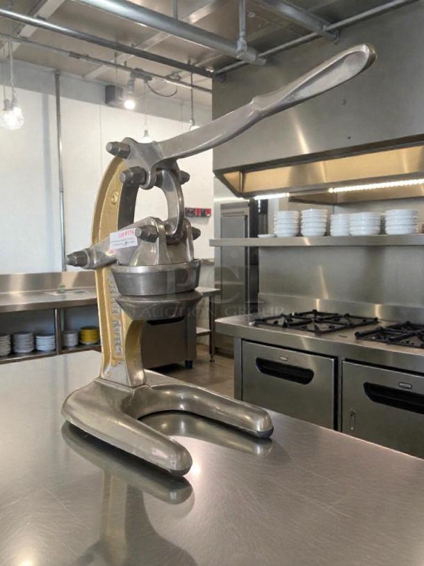 Heavy-duty commercial manual fruit press in excellent condition, fully tested, with sturdy metal construction and ergonomic handle.