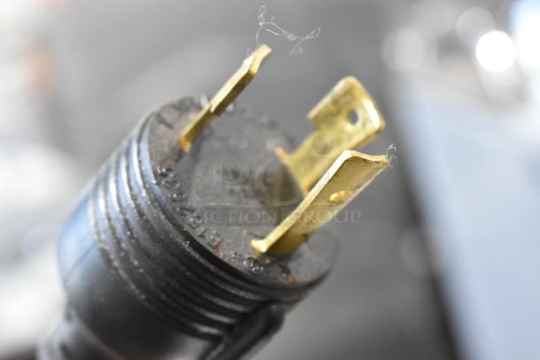 Close-up of a power plug from a Schaerer SCAP Coffee Art Automatic Coffee Machine, showing metal prongs and visible wear.