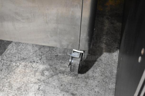 Stainless steel Stoelting ice cream machine caster on a concrete floor, part of commercial model F231-18I2YGAD1.