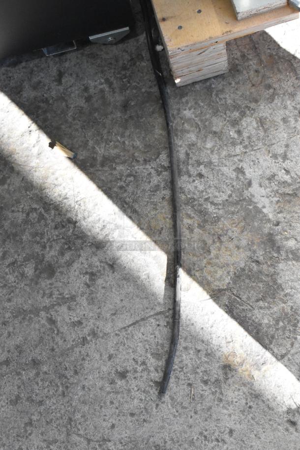 The image shows a power cable lying on the floor, next to a wooden platform.