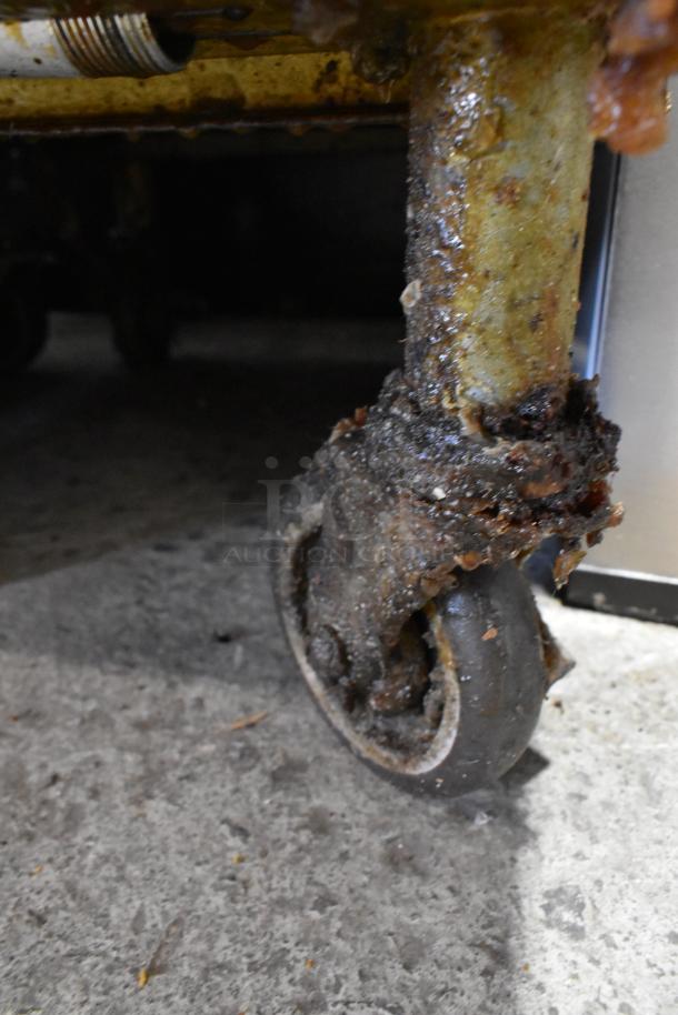 Pitco Frialator SG18 commercial deep fryer caster, showing signs of heavy use and grease buildup.