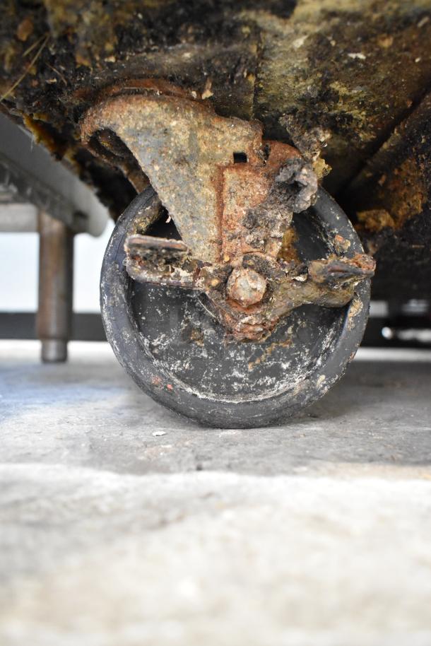 Close-up of a rusted commercial caster on a True TWT-27 undercounter cooler. Condition shows significant wear.