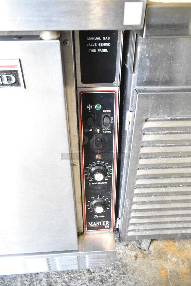 Garland Master 200 stainless steel convection oven, solid doors, thermostatic controls, metal racks, "manual gas valve behind" sign.