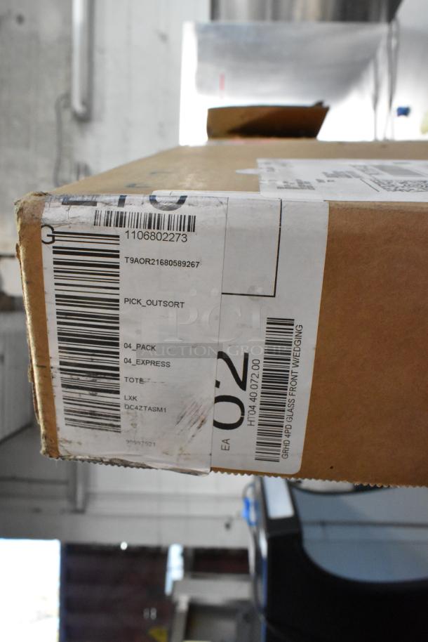 Cardboard box with shipping labels, marked "BRAND NEW SCRATCH AND DENT! Unit." Visible barcodes and tracking numbers.