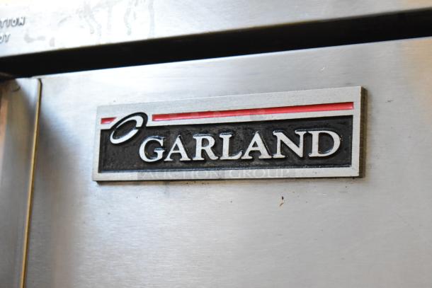 2 Garland Master 200 stainless steel commercial convection ovens with solid doors, metal racks, thermostatic controls, on casters.
