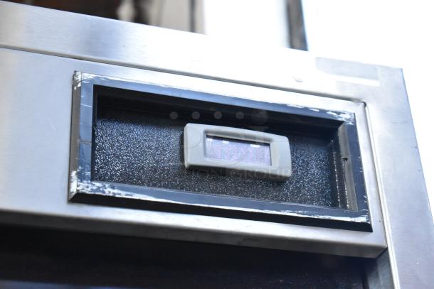 Delfield stainless steel commercial 2-door reach-in cooler detail, left door locked, 115 volts, 1 phase, visible wear.