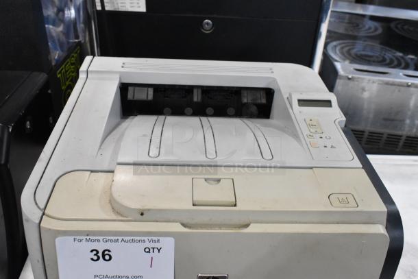 HP LaserJet P2055dn countertop printer showing slight wear, control panel buttons, and auction label. Ideal for office use.