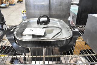 Farberware FW61100018857 electric skillet, metal, glass lid, 120 volts, 1 phase, on metal rack, condition visible.