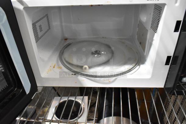 Farberware EM720CGA-B countertop microwave with glass plate inside. Visible stains indicate used condition. 120 volts, 1 phase.