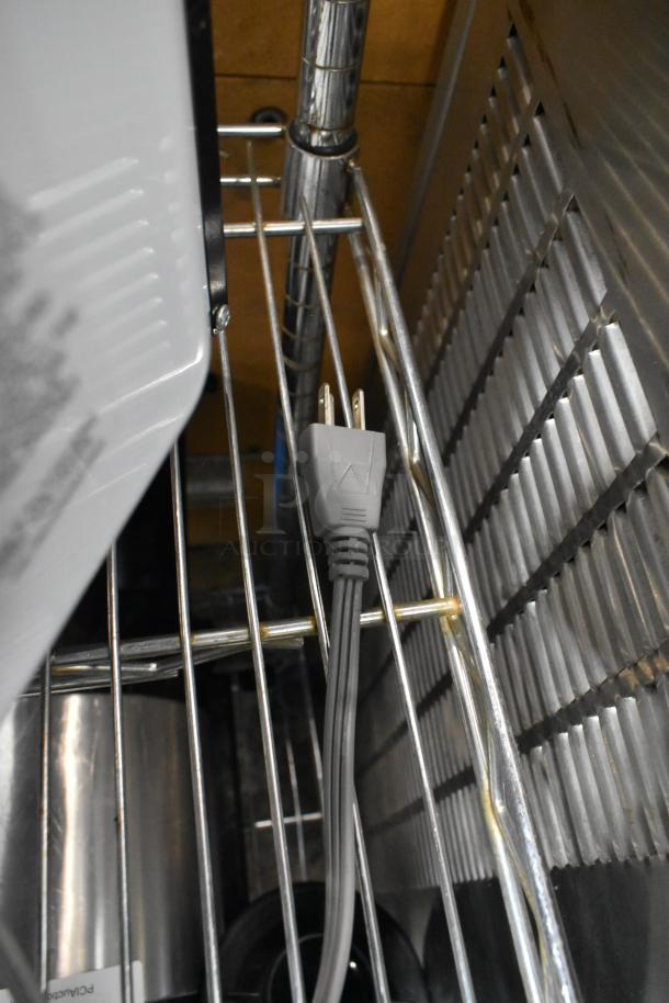 Farberware EM720CGA-B microwave plug on a metal shelf, showcasing power compatibility.